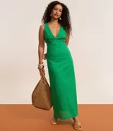 Vestido midi de algodón color verde esmeralda con diseño de laser cut y recortes en la cintura. Presenta escote en V profundo y tirantes finos que se cruzan en la espalda con esferas decorativas.