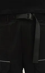 Bermuda negra de calce relax-fit, confeccionada en nylon y spandex, con tejido repelente al agua. Presenta cintura con elástico y cordón de ajuste, bolsillos delanteros con fuelle y grandes bolsillos cargo laterales con tapa. Incluye un cinturón de cinta ajustable con hebilla de plástico.