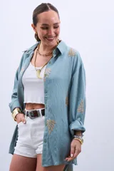 Camisa celeste con bordado de hojas color dorado, de corte holgado y manga larga con puños abotonados.