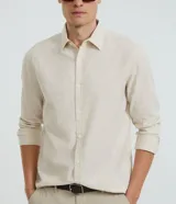 Camisa celeste de lino con cuello camisero, abotonadura frontal y mangas largas.