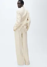 Conjunto color crema compuesto por un blazer de doble botonadura con solapas de muesca y bolsillos de parche, y un pantalón de corte wide leg con pinzas y cierre oculto.