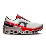 Championes de running On Cloudmonster 2, color blanco con detalles en negro, rojo y rosa.