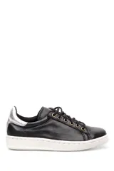 Zapatillas bajas negras de cuero liso, con cordones y suela blanca.