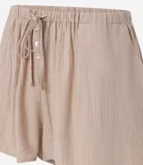 Short de playa suelto color beige, confeccionado en viscosa certificada, con cintura elástica ajustable mediante lazo y bolsillos laterales.