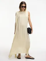 Vestido largo color crema, de corte amplio y cuello redondo. Presenta tajos laterales verticales.