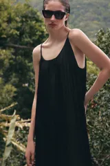 Mono de mujer color marrón oscuro, con escote redondo y tirantes finos. El tejido es satinado y plisado verticalmente. El pantalón es estilo bombacho con bajo abullonado ajustado con botón.