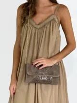 Bandolera color crudo con textura tipo piel de cocodrilo, solapa con cierre imantado y correa de cadena dorada.