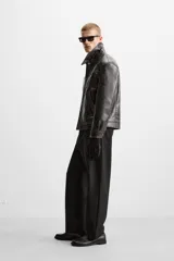 Pantalón negro de corte recto con cintura elástica, bolsillos delanteros y traseros. Cierre frontal con cremallera y botón.
