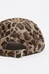 Gorra de béisbol con estampado de leopardo en tonos grises y negros. Presenta un bordado frontal en color celeste claro.
