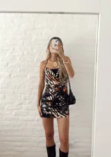 Minivestido ajustado con estampado animal print en tonos naranja, marrón y negro. Diseño con escote drapeado con detalle de encaje negro y tirantes finos.