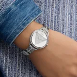Reloj Guess para mujer, con caja plateada de 30mm con cristales y esfera plateada con logo triangular de la marca. Malla de acero plateada con eslabones autoajustables.