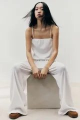 Top corto blanco de punto crepé con broderie, corte holgado, escote cuadrado y breteles finos ajustables.