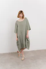 Vestido midi de lino con corte relajado y silueta fluida. Presenta escote redondo, mangas 3/4 y bolsillos laterales. Diseño minimalista y atemporal ideal para el verano.