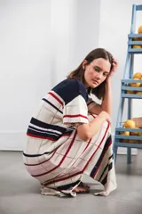 Vestido largo de tejido calado con rayas horizontales en color crudo, azul marino y rojo. Tiene tajo lateral y logo bordado en la manga.