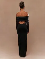 Vestido largo negro con escote bardot, mangas largas de tul semitransparente y silueta ajustada.