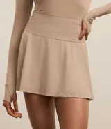 Short pollera deportivo color beige, confeccionado en microfibra ligera, con cintura ancha y calza interna.