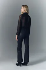 Pantalón jean de tiro medio, confeccionado en denim azul con coating negro que le da apariencia de cuero. Es ajustado en la cintura y levemente acampanado desde la cadera al ruedo.