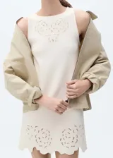 Vestido corto color crema, sin mangas, con cuello redondo y detalles calados en el cuello y ruedo.