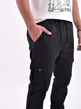 Pantalón tipo jogger cargo de color azul marino, con cintura elástica y cordón ajustable. Presenta bolsillos cargo a los lados de los muslos y puños elásticos en los tobillos.