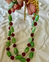 Collar corto con cuentas de piedra verde, cuentas de piedra roja y detalles dorados.