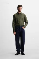 Camisa blanca de corte regular, cuello italiano, manga larga con puños abotonados y cierre frontal con botones.