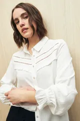 Camisa celeste de manga larga confeccionada en viscosa ligera, con detalles calados en la parte superior y pequeños volados.