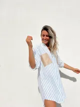 Camisola a rayas verticales azules y blancas, con cuello en V, mangas 3/4 y dos bolsillos cuadrados de gamuza color beige en el pecho.