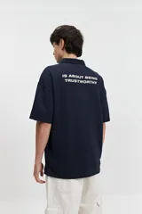 Polo azul marino con textura y corte oversize. Presenta un logo estampado en el pecho y mangas cortas.