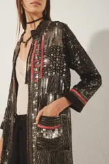 Saco largo abierto de crepe color negro con bordado de lentejuelas, canutillos y mostacillas plateadas. Tiene mangas largas, cuello redondo, bolsillos delanteros y forrería de jacquard a tono.
