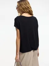 Remera negra con botones en la parte delantera y escote amplio, de mangas cortas. Confeccionada en viscosa y lino.