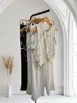 Conjunto de chaleco y pantalón color crudo con bordados de lentejuelas plateadas. El chaleco es sin mangas y el pantalón es de corte recto.