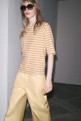 Camiseta a rayas horizontales color naranja y blanco, de manga 3/4 y cuello redondo.