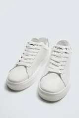 Zapatillas deportivas blancas con detalle de color marrón en el talón y suela con volumen.