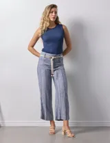 Pantalón de lino a rayas verticales azules y blancas, con corte ancho, pretina con pasadores, cierre y botones. Incluye cinto de soga con nudo.