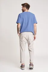 Pantalón de vestir color beige, de corte recto, con bolsillos laterales y traseros. Se ajusta a la cintura con cinturón de cuero marrón.