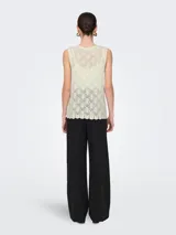 Chaleco de punto color crema con escote en V y lazo delantero. Diseño estructurado y calce ajustado.