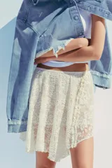 Falda corta de encaje color crema con forro interior. Presenta cintura elástica y bajo asimétrico con terminación en picos.