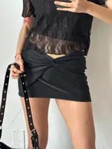 Minifalda plateada con textura brillante y detalle de nudo en la parte delantera.