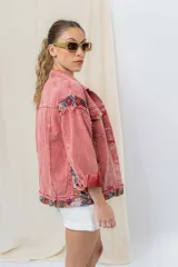Campera de jean oversize, color rojo desgastado, con aplicaciones de tapicería multicolor de estilo étnico en hombros y ruedo, y terminaciones desflecadas.