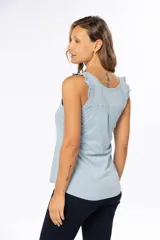 Musculosa celeste de algodón y poliéster, con breteles anchos con volados y tres botones en el escote.
