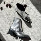 Bota corta plateada estilo texana, con caña media, puntera afilada y taco bajo cuadrado.
