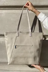 Bolso grande tipo tote de cuero color marrón con costuras decorativas en los laterales, forro interior con bolsillo para celular y bolsillo con cierre. Incluye bolsillo trasero con cierre y correas largas para colgar del hombro.