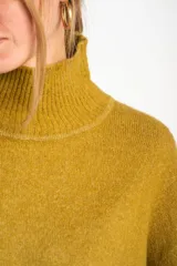 Polera color crema de tejido de punto, con cuello alto y mangas largas.