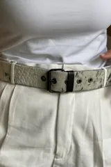 Cinturón con estampado animal print en blanco y negro, hebilla metálica cuadrada color negro y pasador de cuero negro.