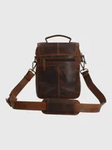 Maletín pequeño tipo bandolera o morral de cuero marrón oscuro con efecto envejecido. Posee asa superior y correa ajustable para llevar al hombro. Presenta un bolsillo frontal con solapa curva y el logo de Hush Puppies grabado.