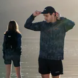 Cortaviento con estampado camuflado en tonos grises y negros, con cierre de cremallera frontal, capucha ajustable y bolsillo con cierre en el pecho.