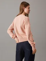Sweater de punto color salmón, de corte relaxed, con cuello redondo y monograma bordado de Calvin Klein en el pecho.