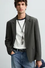 Blazer regular fit color gris oscuro confeccionada en tejido con estructura. Cuello con solapas de muesca y manga larga. Bolsillos de solapa en cadera. Cierre frontal de botonadura.
