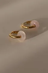 Aros dorados tipo argolla con dije de piedra natural rosa.