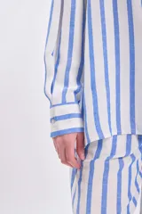 Camisa celeste y blanca a rayas verticales, de corte holgado y manga larga.